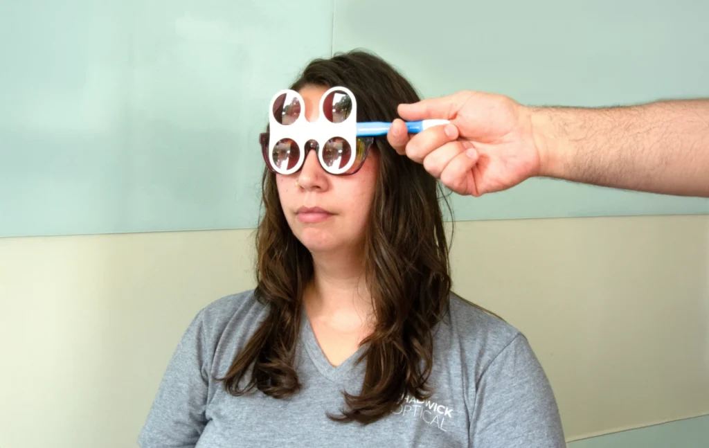 Woman undergoing an optical test with specialized glasses in a clinic setting.