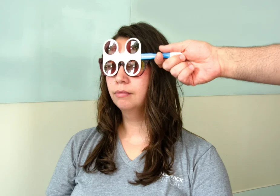 Woman undergoing an optical test with specialized glasses in a clinic setting.