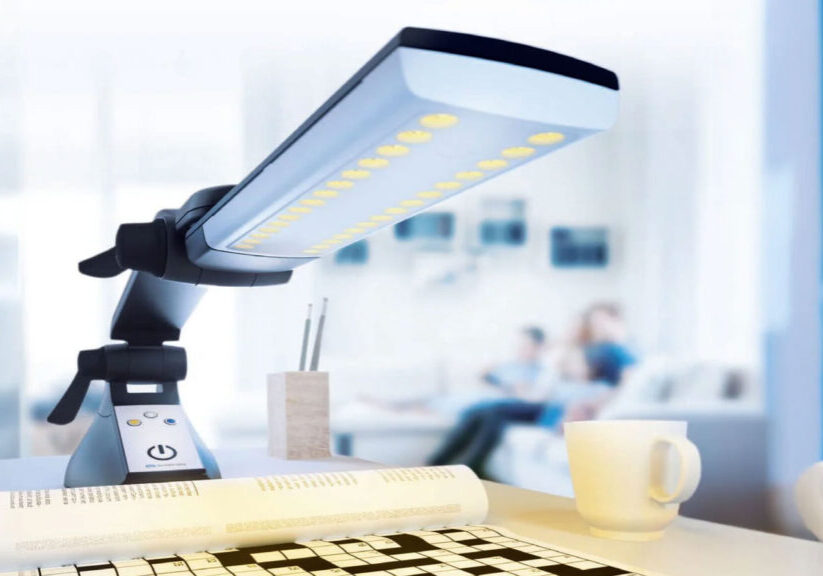 LED desk lamp illuminating a crossword puzzle on a white table with a cup and pencils in a modern office setting.